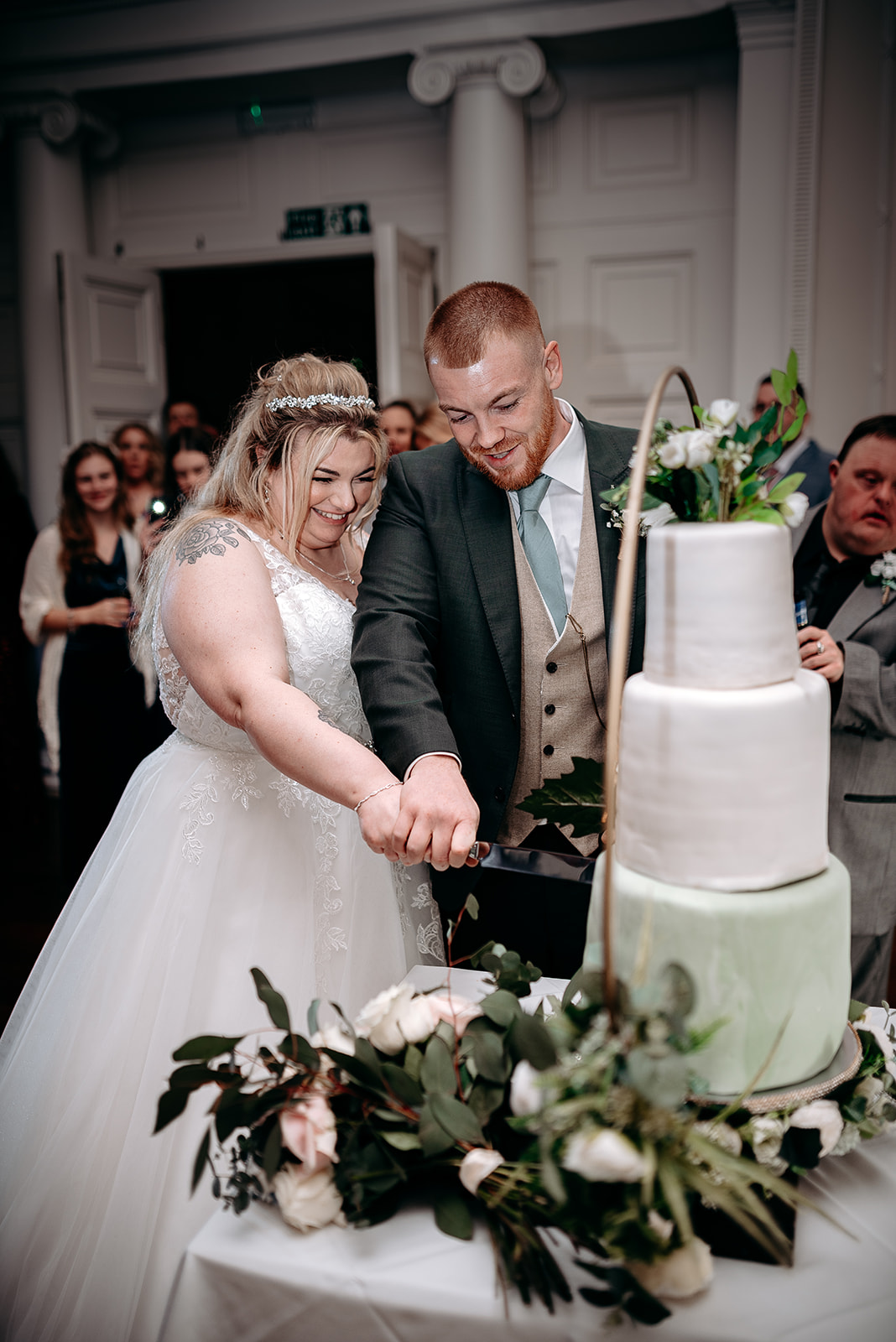 Bride and groom cutting cake surrounded by guests at Rowton Castle