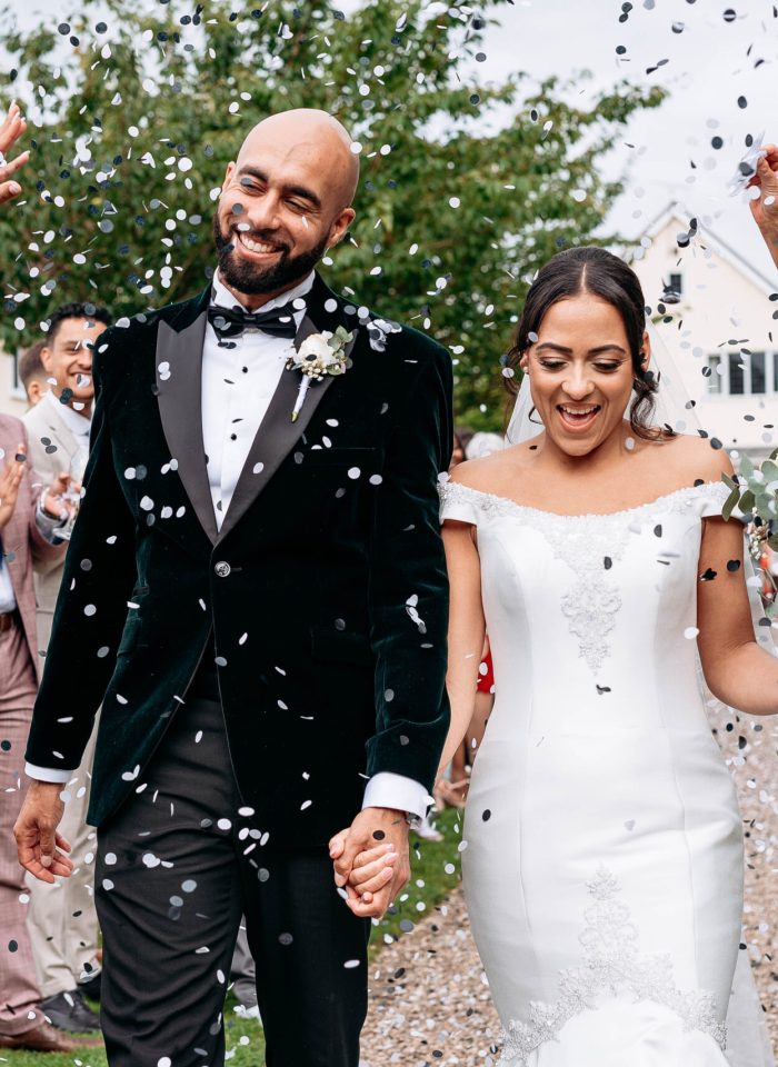 Natural wedding photo of couple walking hand in hand through confetti - how far in advance to book wedding photographer