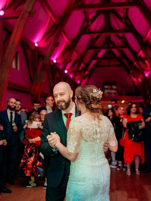 Candid reception photo at The Mill Barns – guests dancing and laughing.