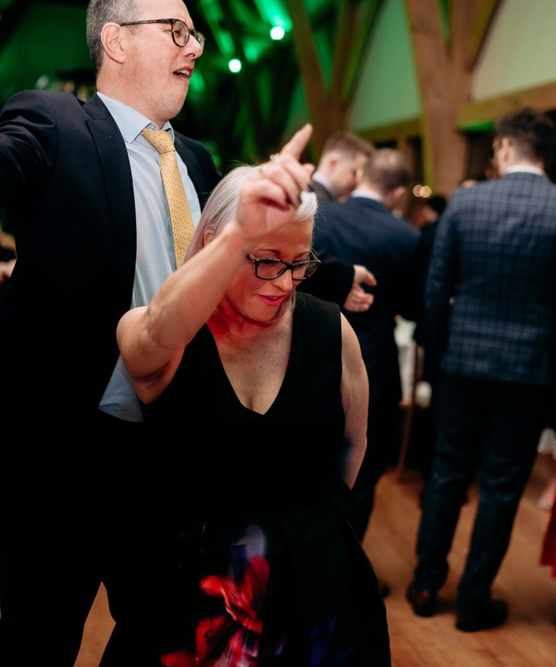 Candid reception photo at The Mill Barns – guests dancing and laughing.