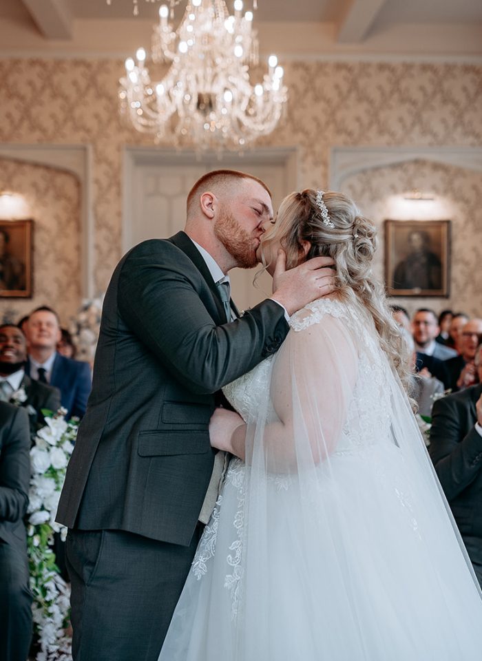 rowton castle wedding photography Bride and groom first kiss surrounded by guests at Rowton Castle
