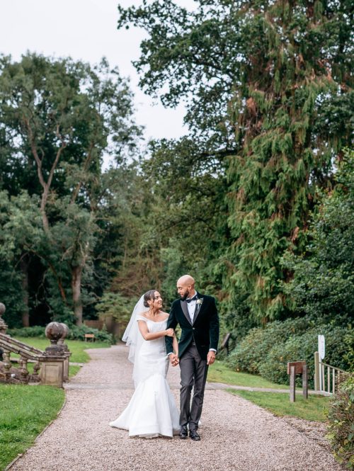 Wedding photographer bride and groom walking through grounds of their wedding venue Hogarths