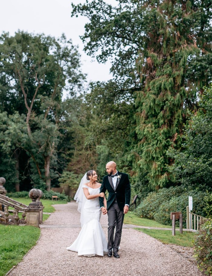 Wedding photographer bride and groom walking through grounds of their wedding venue Hogarths