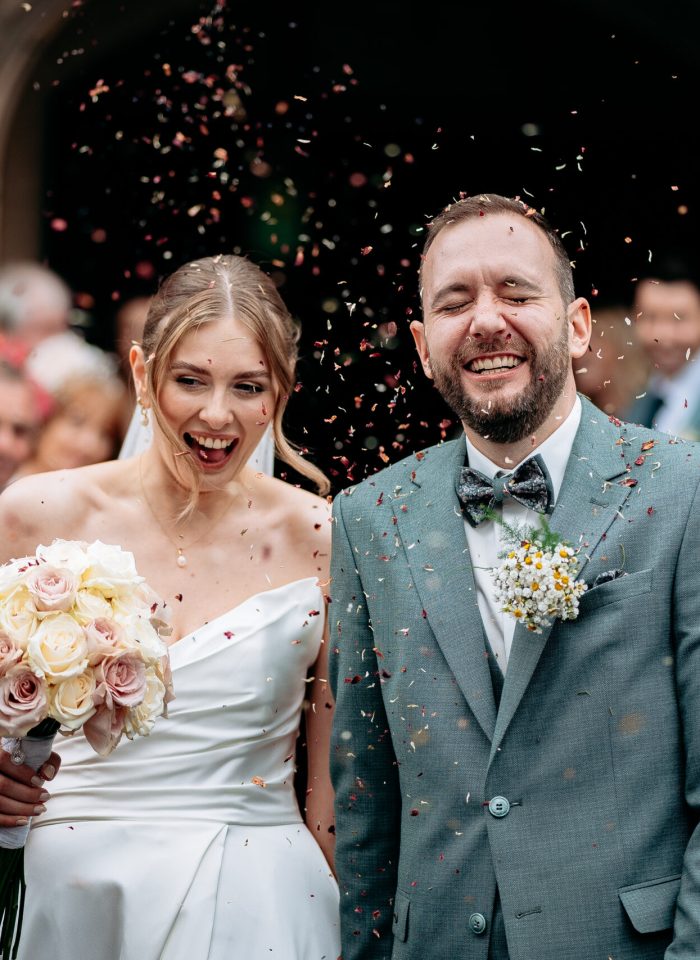 Natural wedding photo of couple walking hand in hand through confetti - how far in advance to book wedding photographer
